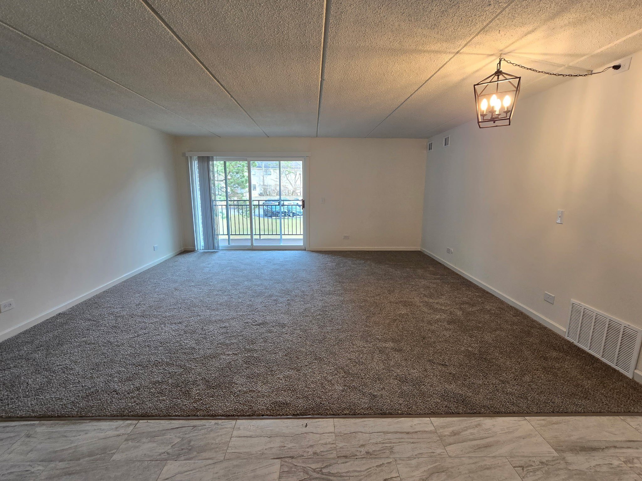 A room with a carpeted floor and a window letting in natural light.